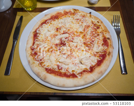 Pizza with cheese lies on the table with a fork and knife. 53118103