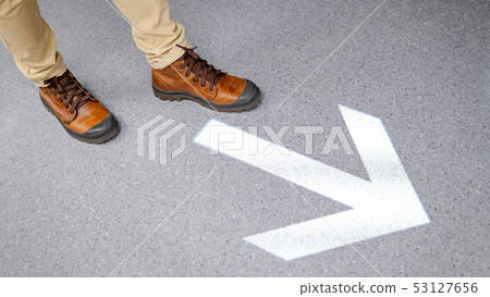 Feet stepping over arrowhead sign on the floor Feet stepping over arrowhead sign on the floor 53127656
