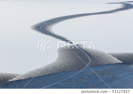 Snow on cracked frozen lake ice surface 53127957