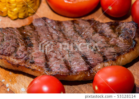 Close up freshly grilled steak on wood with tomatoes and corn Close up freshly grilled steak on wood with tomatoes and corn 53128114