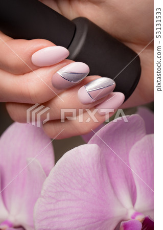 Purple neat manicure on female hands on flowers background. Nail design Purple neat manicure on female hands on flowers background. Nail design 53131533