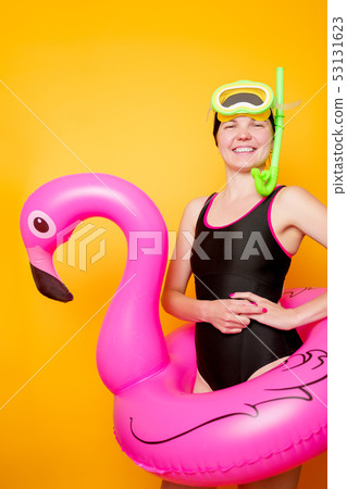 Photo of woman with scuba and in swimsuit with life preserver on empty orange background Photo of woman with scuba and in swimsuit with life preserver on empty orange background 53131623