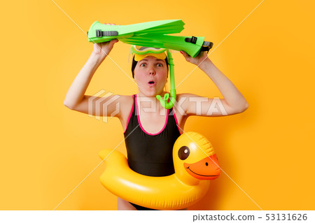 Image of woman with flippers in hands, swimming mask and with life preserver on empty orange Image of woman with flippers in hands, swimming mask and with life preserver on empty orange 53131626