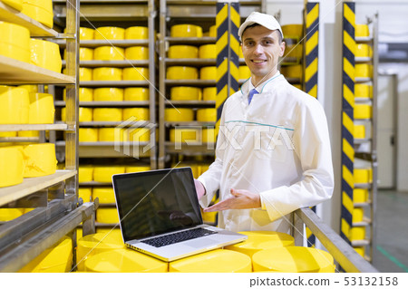 Portrait of man in a white robe and a cap standing in production department of dairy factory with 53132158