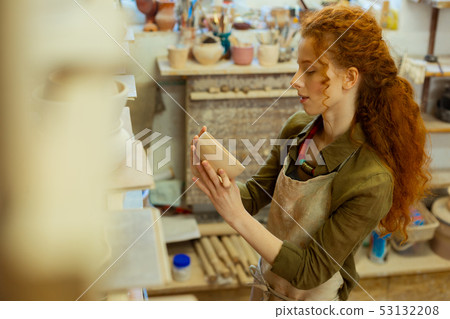 Satisfied long-haired pottery master observing her first creations 53132208
