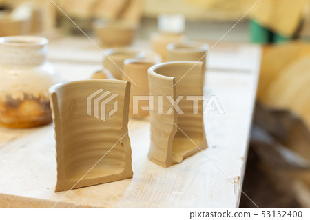Fresh unprocessed clay pot being separated on two pieces Fresh unprocessed clay pot being separated on two pieces 53132400