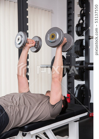 Men giving dumbbells at the gym Men giving dumbbells at the gym 53137550