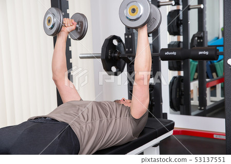 Men giving dumbbells at the gym Men giving dumbbells at the gym 53137551