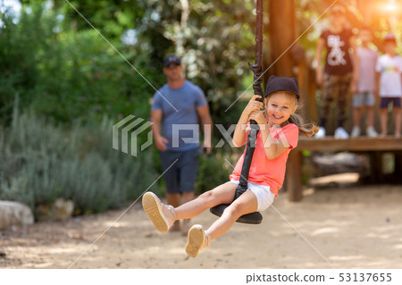 smiling girl riding a bungee in a park on the playground 53137655
