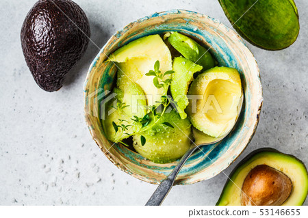 Peeled avocado halves in a bowl, top view.  53146655