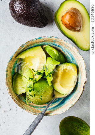 Peeled avocado halves in a bowl, top view.  53146656
