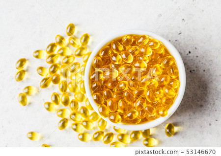 Fish oil capsules (omega 3) in white bowl on gray Fish oil capsules (omega 3) in white bowl on gray 53146670