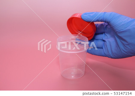 A hand in a blue latex glove holds a container A hand in a blue latex glove holds a container 53147154