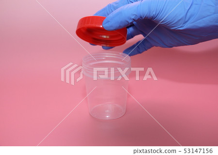 A hand in a blue latex glove holds a container A hand in a blue latex glove holds a container 53147156