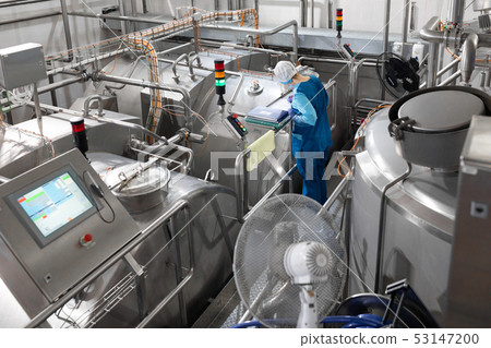 worker in a blue robe and a cap inspect the production department of dairy factory 53147200