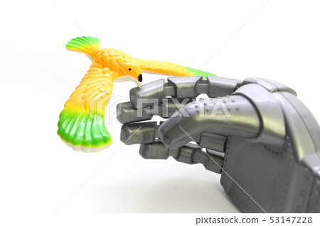 A little bird is sitting on the finger of a robot. 53147228