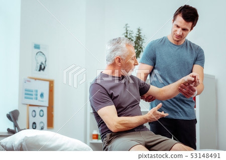 Nice young man holding hand of his aged patient 53148491