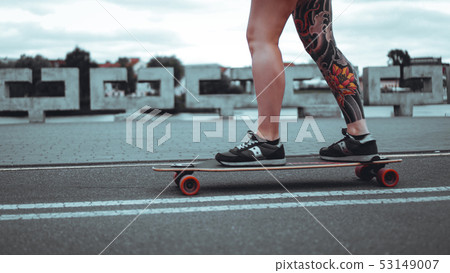 Beautiful young girl with tattoos with longboard 53149007