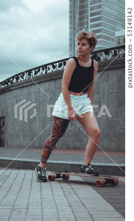 Beautiful young girl with tattoos with longboard 53149142