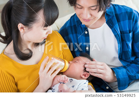 一對年輕夫婦養育嬰兒在奶瓶中喝牛奶養育孩子 一對年輕夫婦養育嬰兒在奶瓶中喝牛奶養育孩子 53149925