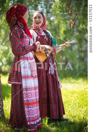 Two young woman in traditional russian clothes standing in the forest and look at each other. One of Two young woman in traditional russian clothes standing in the forest and look at each other. One of 53157015