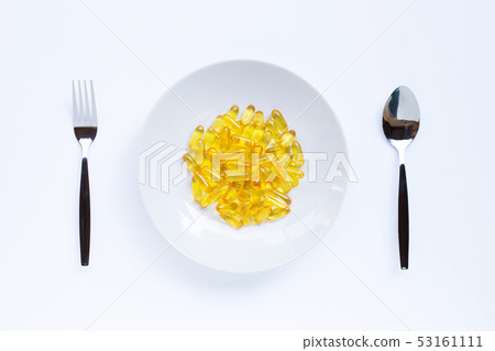 Fish oil capsules on white dish, folk and spoon on 53161111