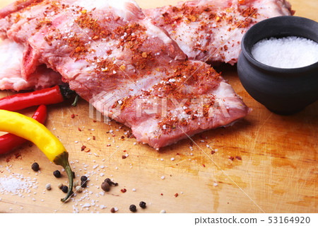 Raw Ribs on a rustic cutting board with salt, pepper and grinder for spices . copy space. Top View. 53164920