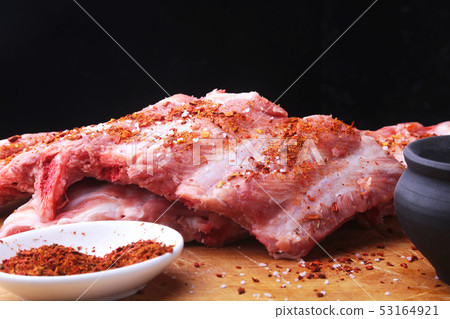 Raw Ribs on a rustic cutting board with salt, pepper and grinder for spices . Black Background for 53164921
