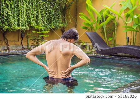 Men's back hurts against the backdrop of the pool. Pool helps with back pain Men's back hurts against the backdrop of the pool. Pool helps with back pain 53165020
