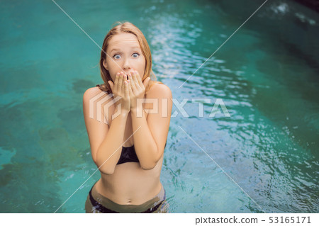 Frustrated young woman having a bad skin in the pool. Due to the fact that chemicals in the pool Frustrated young woman having a bad skin in the pool. Due to the fact that chemicals in the pool 53165171