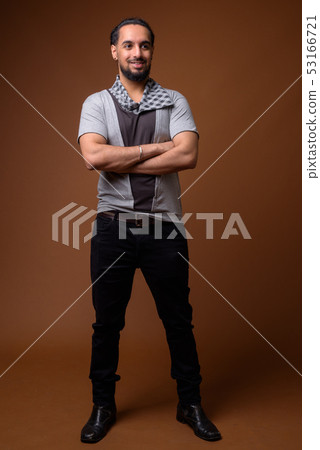 Young bearded Indian man against brown background 53166721