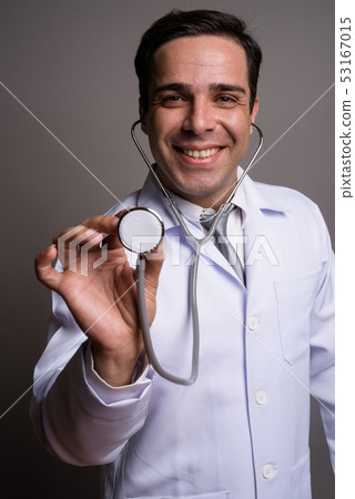 Handsome Persian man doctor against gray background Handsome Persian man doctor against gray background 53167015