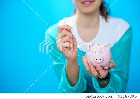 Image of happy woman putting pig in piggy bank 53167399