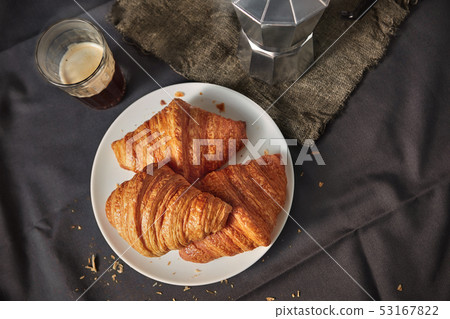 Coffee glass with freshly baked homemade croissants on a dark gray table Coffee glass with freshly baked homemade croissants on a dark gray table 53167822