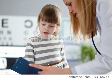Female doctor listening cute little patient and writing registration information on clipboard pad Female doctor listening cute little patient and writing registration information on clipboard pad 53168743