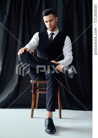 Confident handsome man in elegant suit posing sitting in chair Confident handsome man in elegant suit posing sitting in chair 53168880