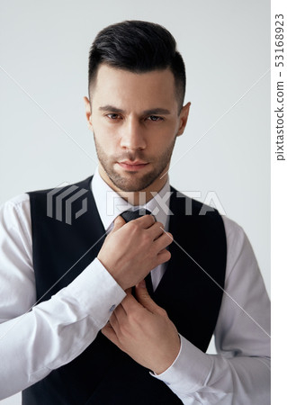 Young handsome man in elegant suit adjust his necktie Young handsome man in elegant suit adjust his necktie 53168923