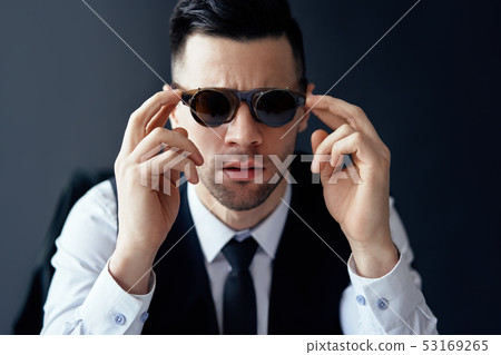Handsome elegant man in retro sunglasses posing in studio Handsome elegant man in retro sunglasses posing in studio 53169265