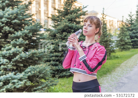 sporty woman drinking water 53172172