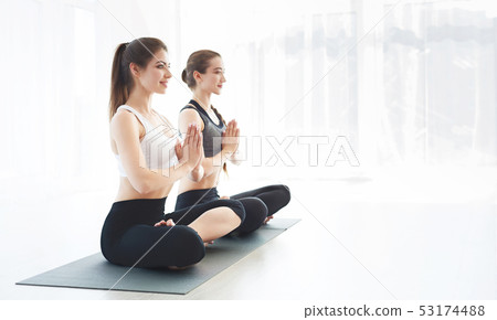 Sporty girls doing yoga and practising yoga together Sporty girls doing yoga and practising yoga together 53174488