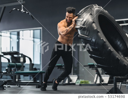 Naked man flipping huge tire at gym 53174698