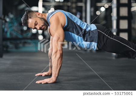 Sporty young man doing pushups in gym Sporty young man doing pushups in gym 53175001