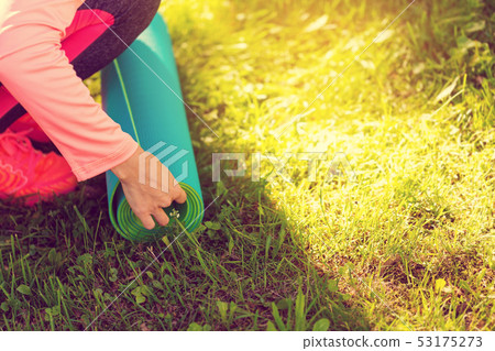 woman after fitness training, folding her mat 53175273