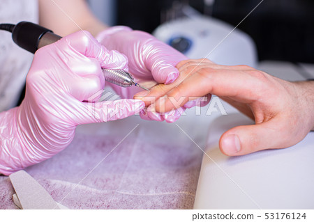 Professional manicure of male hands in a beauty salon close up. Master in gloves makes a manicure 53176124