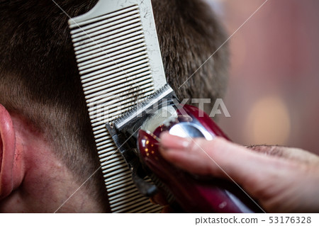 Close up of a male student having a haircut with hair clippers 53176328