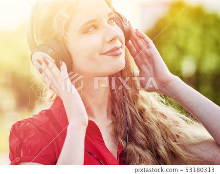 Girl in headphones and red shirt listens to mp3 music 53180313