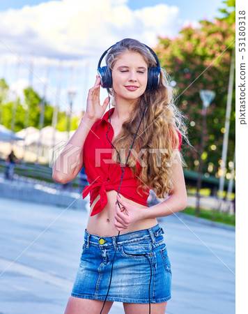 Girl in headphones and denim listens to music with closed eyes Girl in headphones and denim listens to music with closed eyes 53180318