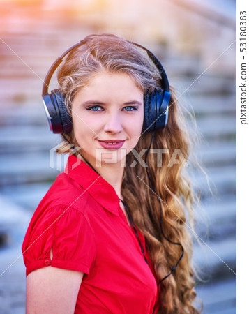 Girl in headphones listens to music walking down stairs Girl in headphones listens to music walking down stairs 53180383