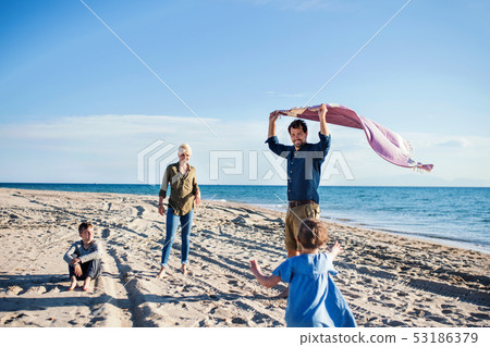 Young family with two small children walking outdoors on beach. Young family with two small children walking outdoors on beach. 53186379