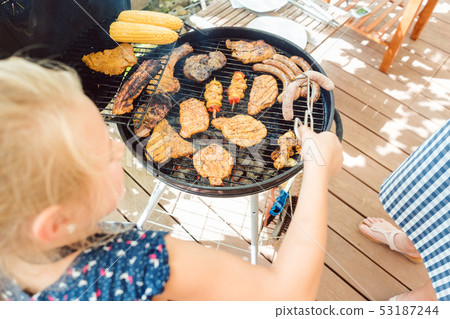 Little girl grilling the meat for the BBQ 53187244